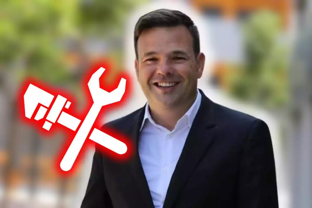 Hombre sonriente con traje oscuro y camisa blanca al aire libre con icono de herramientas en color blanco y borde rojo sobre fondo desenfocado