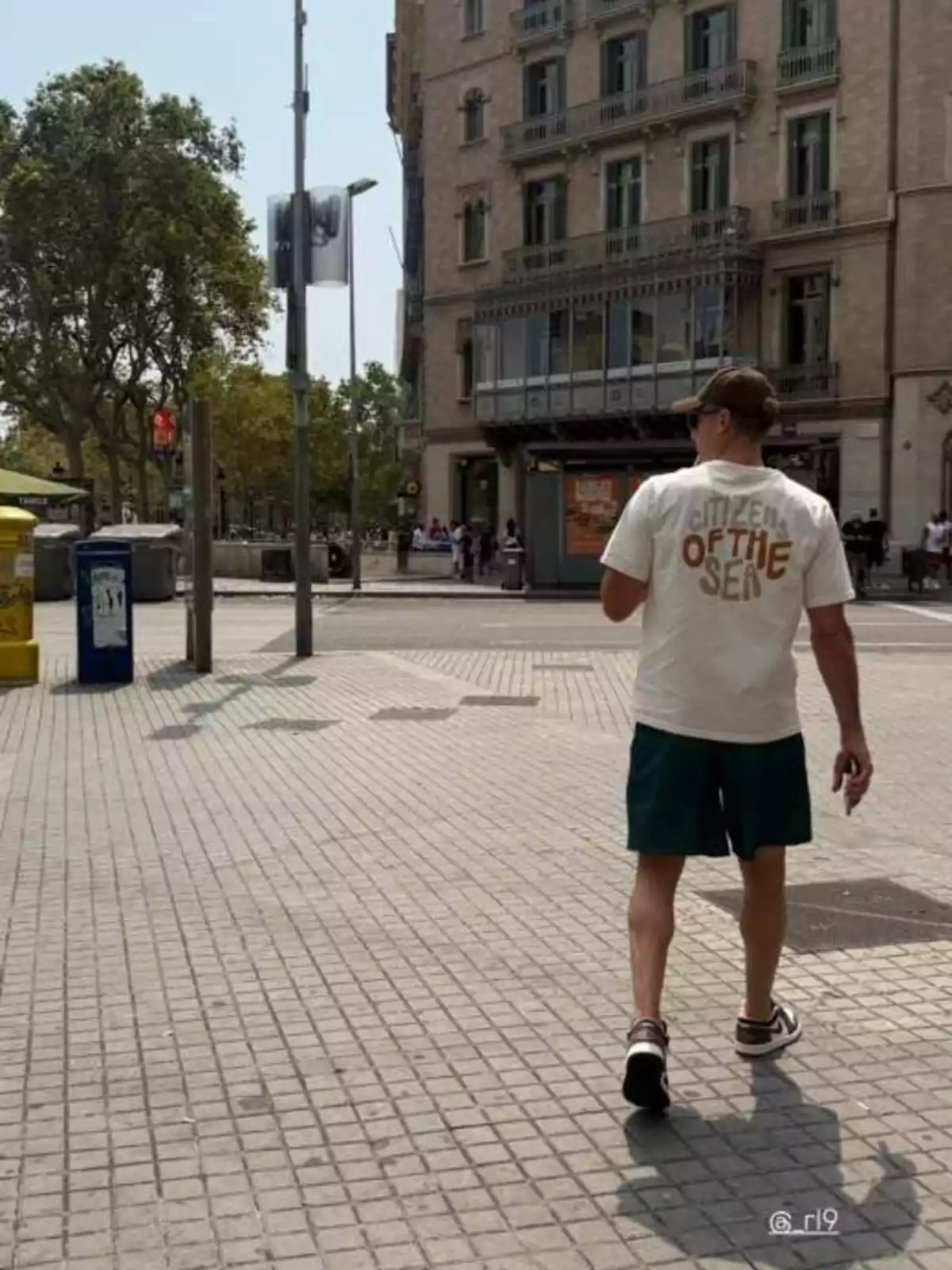 Man walking on a sidewalk in a city with old buildings and trees in the background Man walking on a sidewalk in a city with old buildings and trees in the background