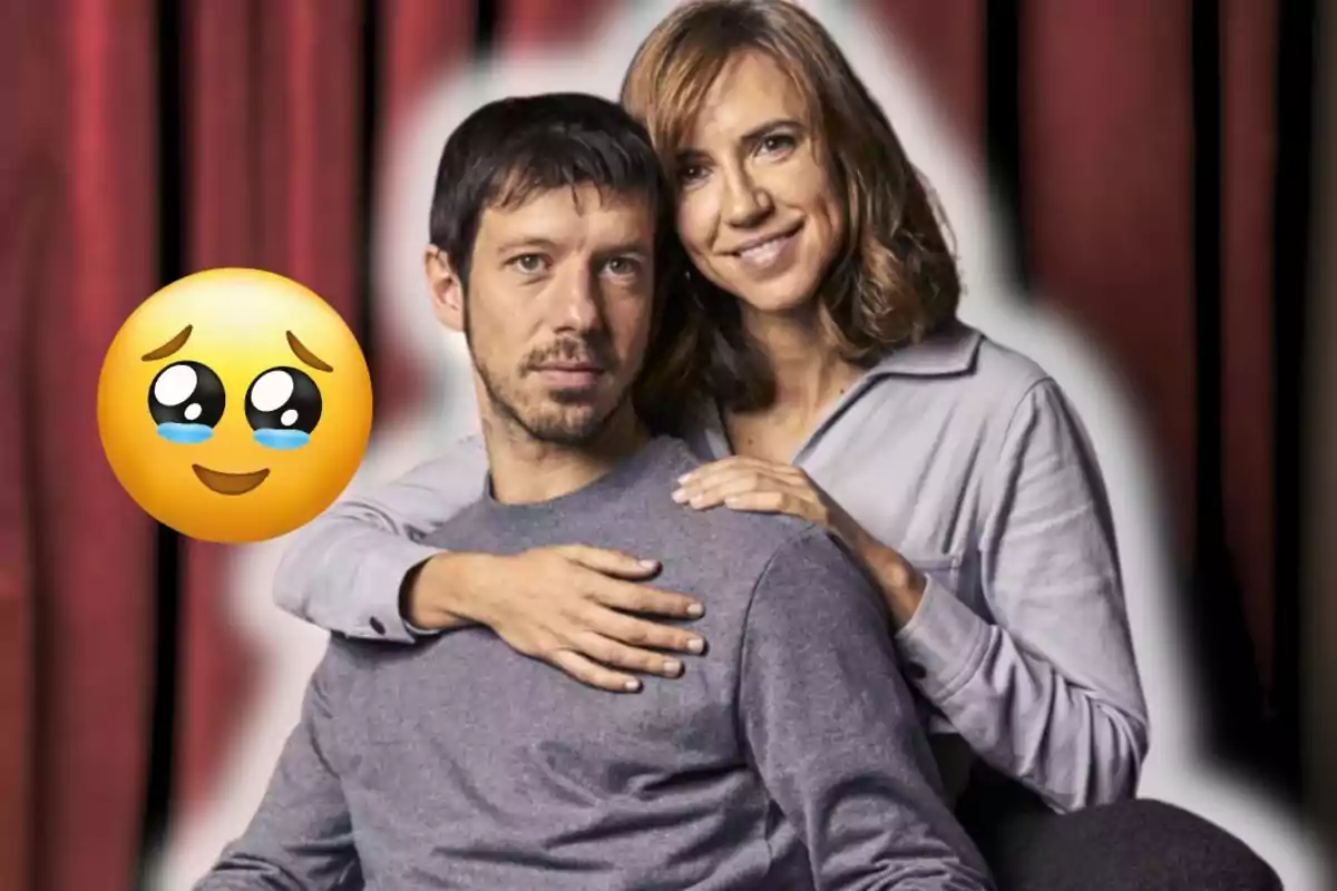 Parella abraçada posant davant d’un fons de cortines vermelles amb un emoji de carona amb ulls brillants i llàgrimes a l’esquerra