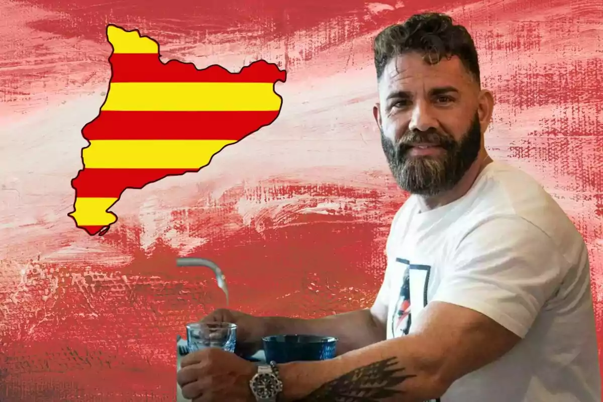 Hombre con barba y tatuaje en el brazo sentado frente a un fondo rojo con la silueta de Cataluña decorada con franjas amarillas y rojas