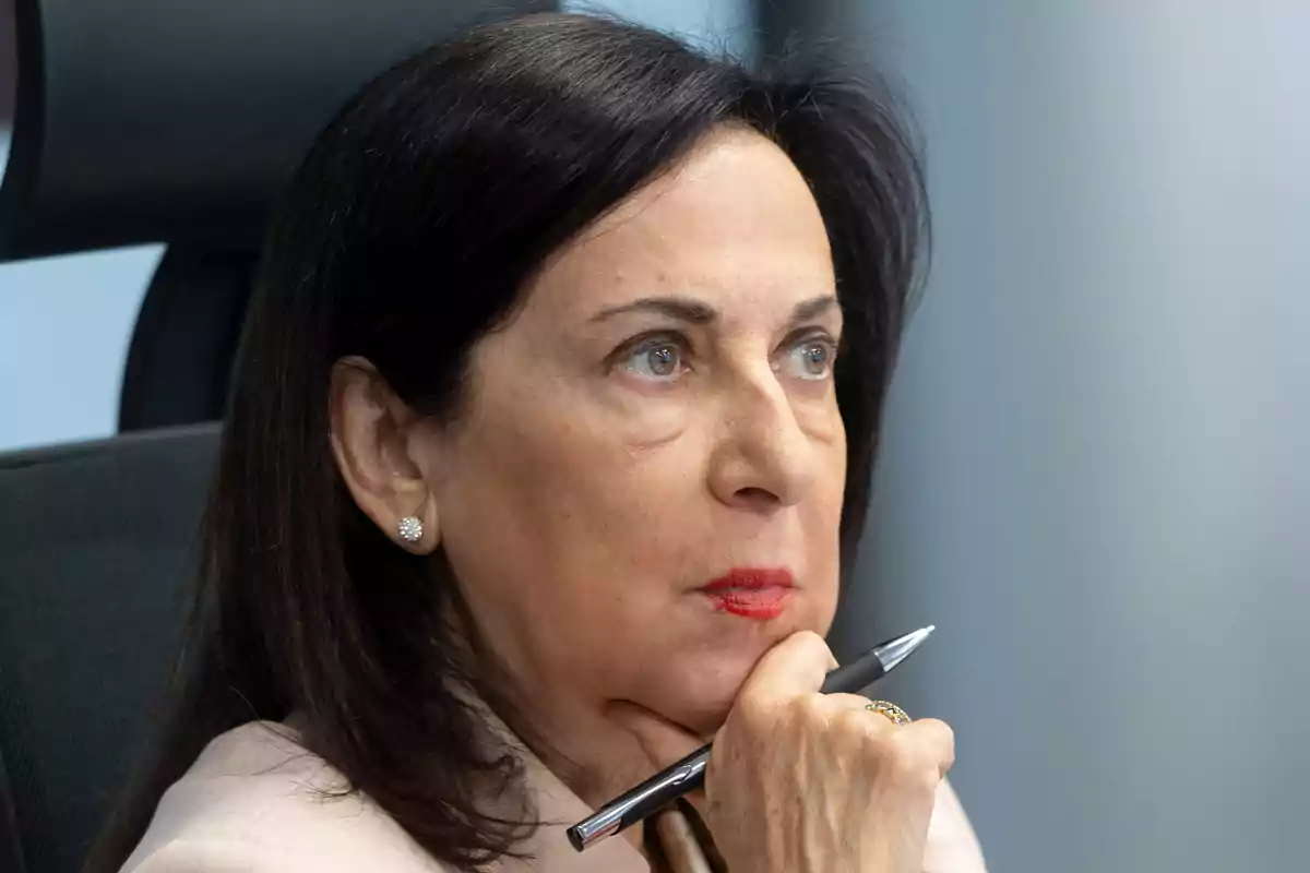 Margarita Robles sentada con expresión pensativa sosteniendo un bolígrafo cerca de su rostro Margarita Robles sentada con expresión pensativa sosteniendo un bolígrafo cerca de su rostro