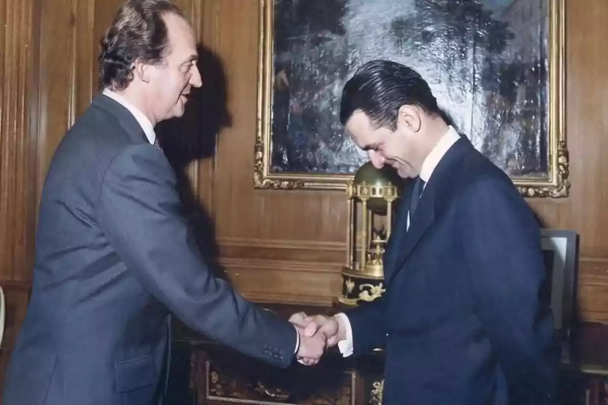 Dos hombres vestidos de traje se dan la mano en una oficina elegante con paredes de madera y un cuadro enmarcado al fondo Dos hombres vestidos de traje se dan la mano en una oficina elegante con paredes de madera y un cuadro enmarcado al fondo