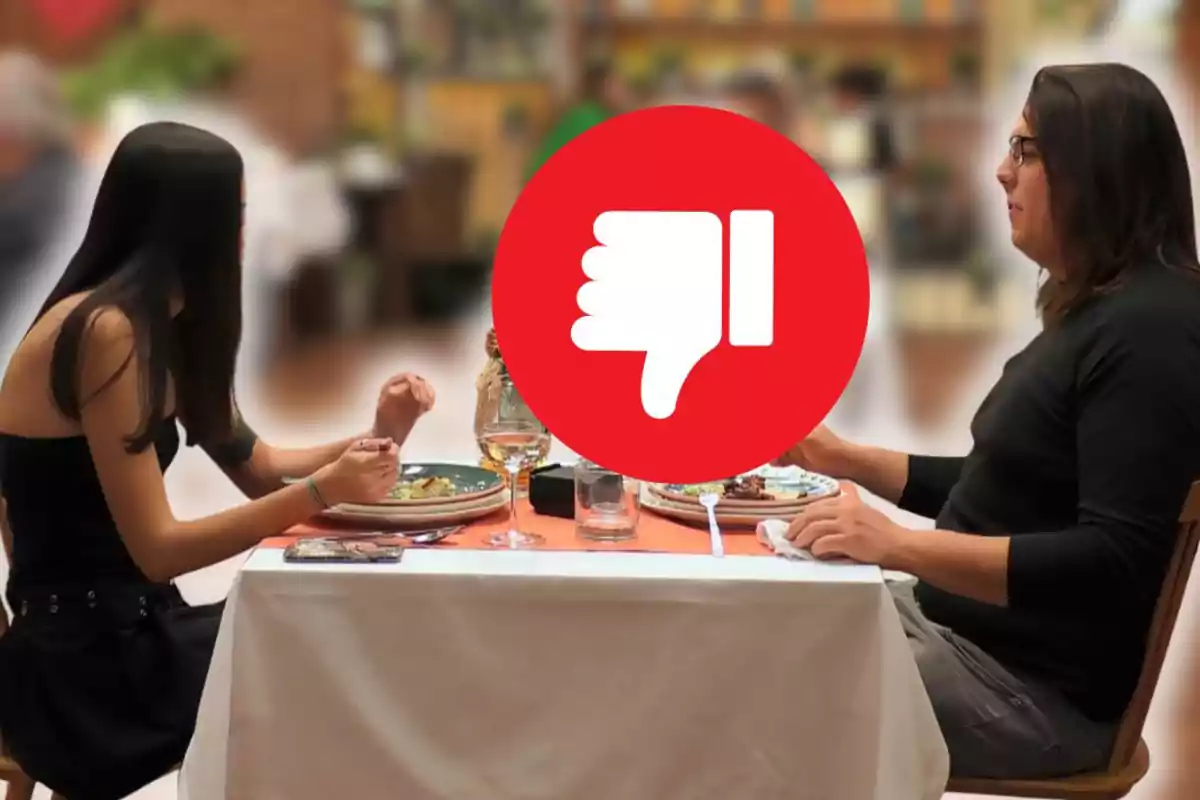 Parella asseguda en una taula de restaurant amb una gran icona de polze avall al centre
