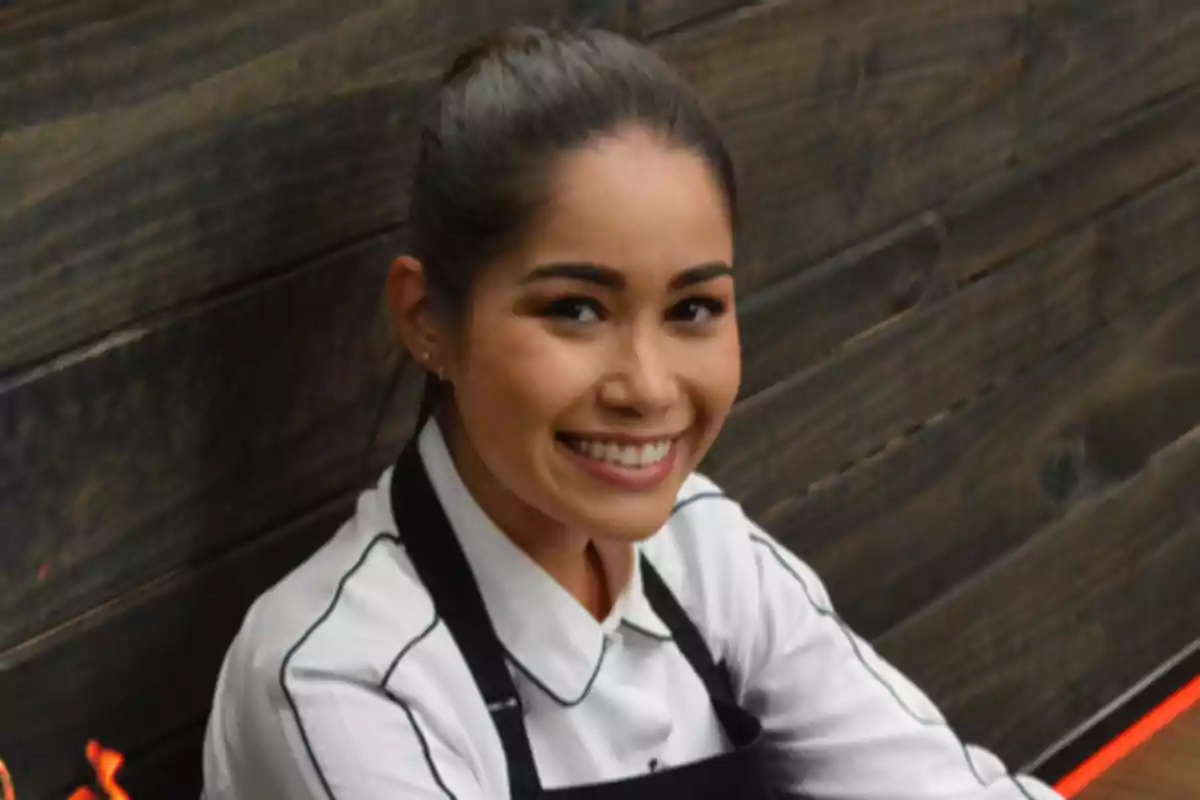 Yanin Campos con cabello recogido y uniforme de chef sonriendo frente a una pared de madera. Captura de 'MasterChef' Yanin Campos con cabello recogido y uniforme de chef sonriendo frente a una pared de madera. Captura de 'MasterChef'