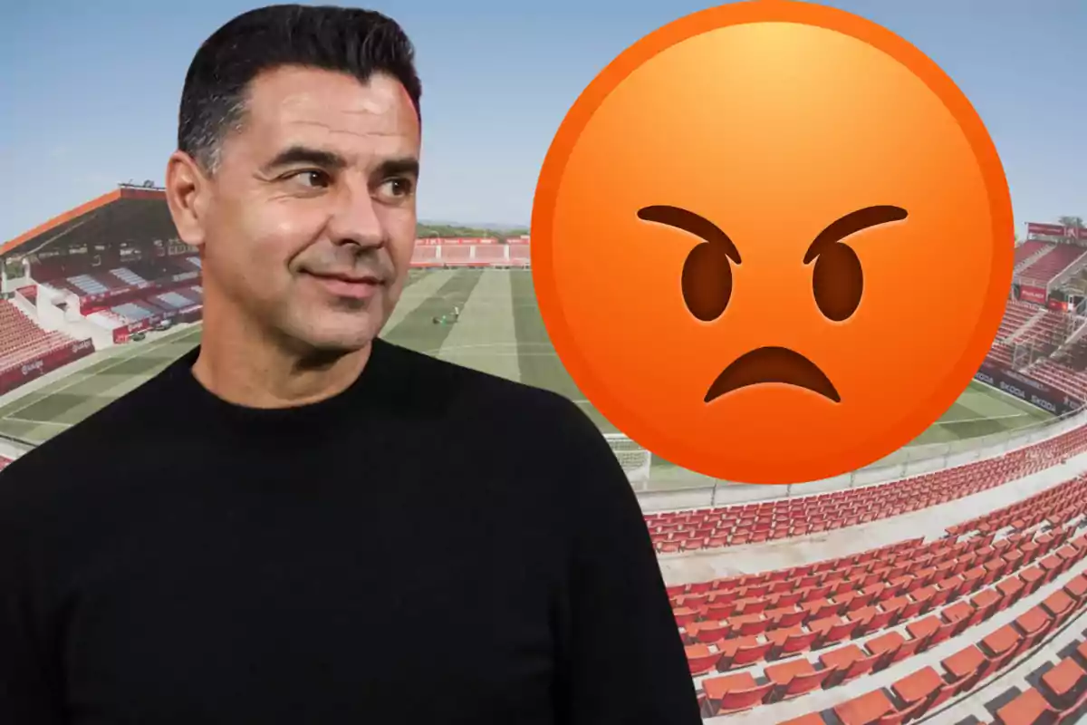 Hombre con suéter negro en un estadio de fútbol junto a un emoji de enojo gigante
