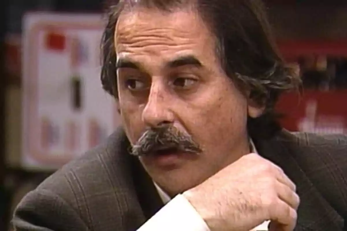 Hombre de mediana edad con bigote y cabello oscuro, vestido con saco, mirando hacia un lado con expresión seria Hombre de mediana edad con bigote y cabello oscuro, vestido con saco, mirando hacia un lado con expresión seria