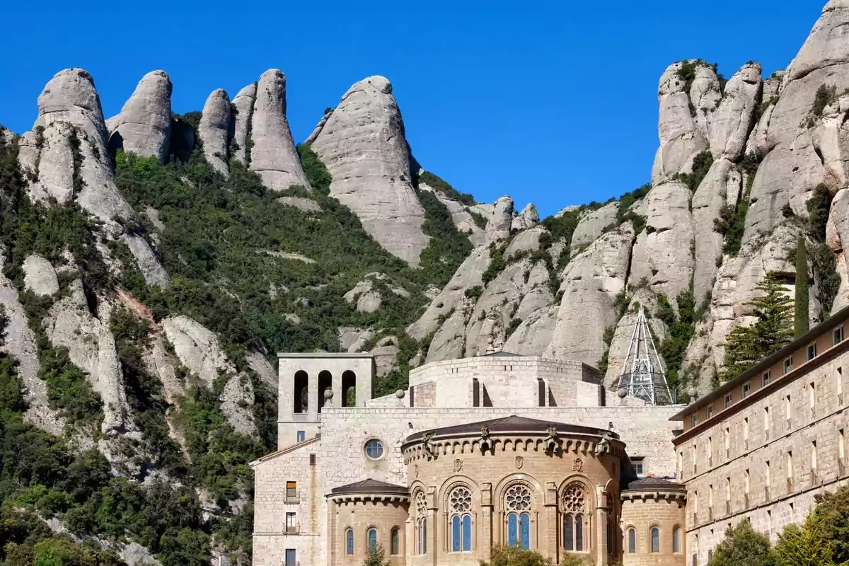 Monestir de Montserrat envoltat de muntanyes rocoses sota un cel blau clar Monestir de Montserrat envoltat de muntanyes rocoses sota un cel blau clar