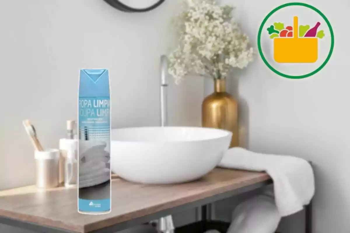 Aerosol d’aroma de roba neta sobre un moble de bany amb lavabo blanc i decoració de flors en gerro daurat Aerosol d’aroma de roba neta sobre un moble de bany amb lavabo blanc i decoració de flors en gerro daurat
