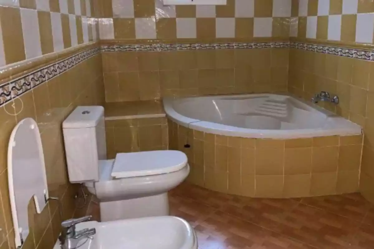 Bany amb rajoles grogues i blanques, banyera de racó, vàter i bidet Bany amb rajoles grogues i blanques, banyera de racó, vàter i bidet