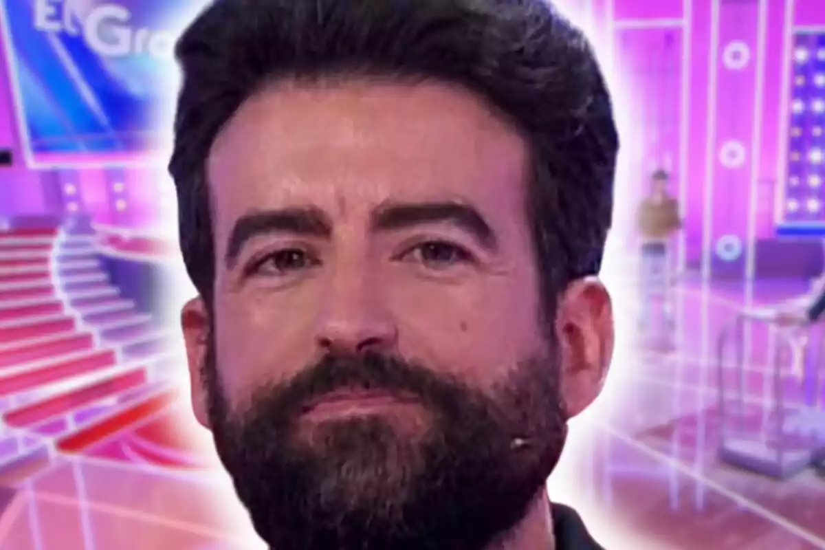 Primer plano de Rafa Castaño con barba y cabello oscuro en un set de televisión con luces y colores brillantes de fondo.