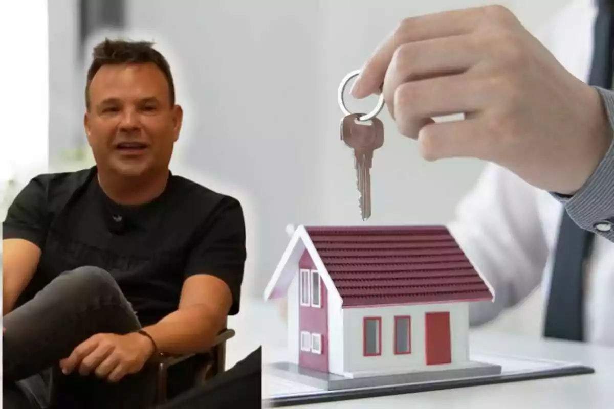Hombre sentado sonriendo junto a una mano que sostiene unas llaves sobre una maqueta de casa Hombre sentado sonriendo junto a una mano que sostiene unas llaves sobre una maqueta de casa