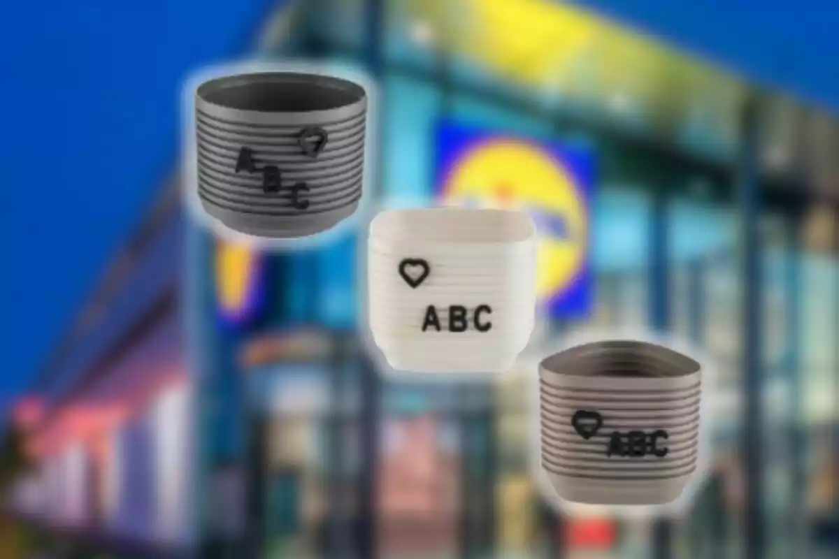 Three small pots in gray and white with raised letters and a heart, set against a blurred store background. Three small pots in gray and white with raised letters and a heart, set against a blurred store background.