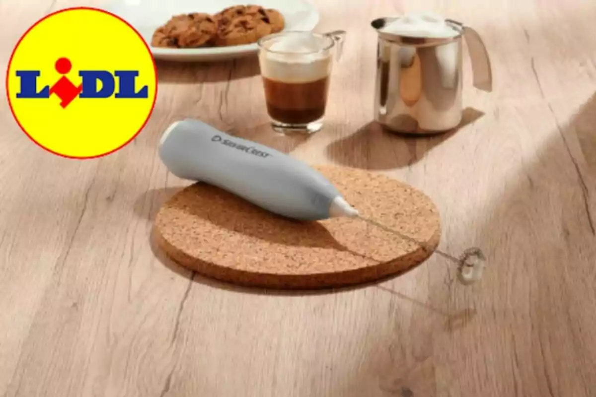 Batedora d’escuma de llet sobre una base de suro amb una tassa de cafè, una gerra de llet escumada i un plat de galetes al fons, al costat del logotip de Lidl Batedora d’escuma de llet sobre una base de suro amb una tassa de cafè, una gerra de llet escumada i un plat de galetes al fons, al costat del logotip de Lidl