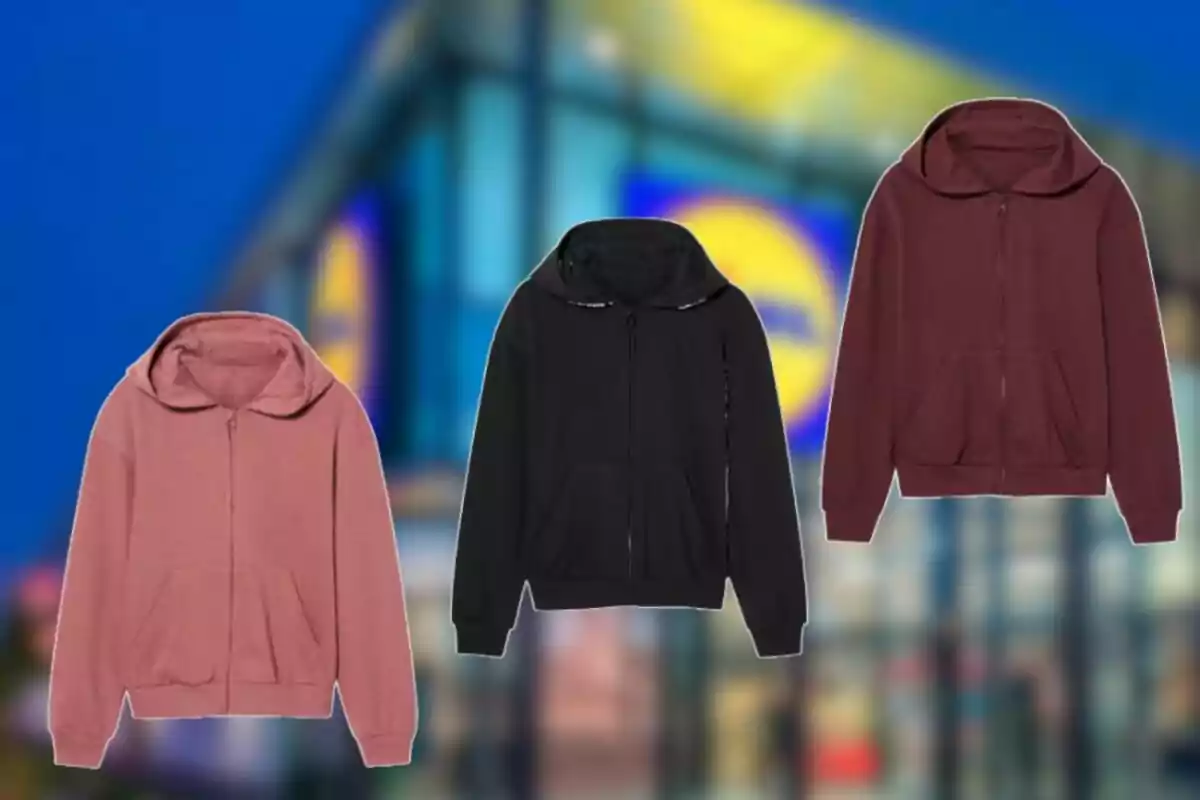 Tres sudaderas con capucha en colores rosa, negro y vino aparecen sobre un fondo desenfocado de una tienda. Tres sudaderas con capucha en colores rosa, negro y vino aparecen sobre un fondo desenfocado de una tienda.