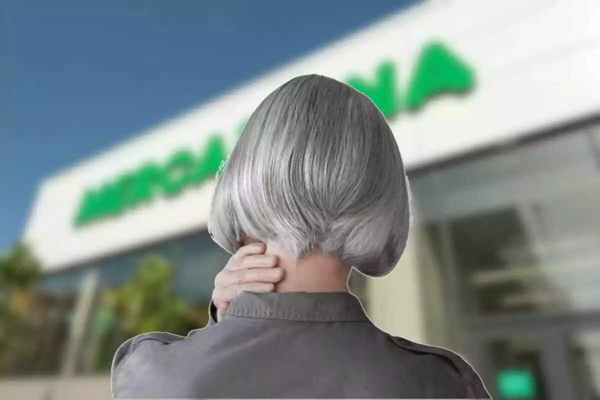 Persona de cabello canoso vista de espaldas tocándose el cuello frente a un edificio con letrero verde desenfocado. Persona de cabello canoso vista de espaldas tocándose el cuello frente a un edificio con letrero verde desenfocado.
