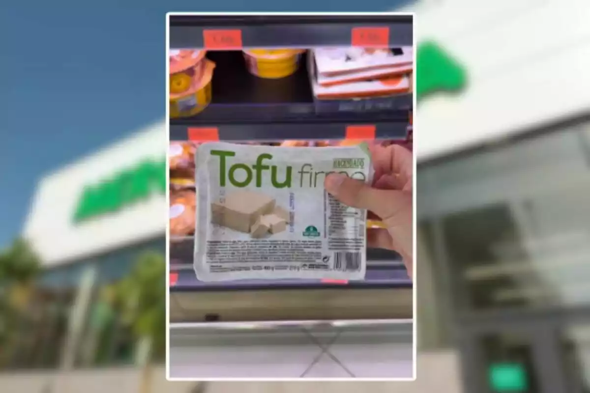 Persona sostenint un paquet de tofu ferm de la marca Hacendado davant d’un prestatge refrigerat en un supermercat Persona sostenint un paquet de tofu ferm de la marca Hacendado davant d’un prestatge refrigerat en un supermercat