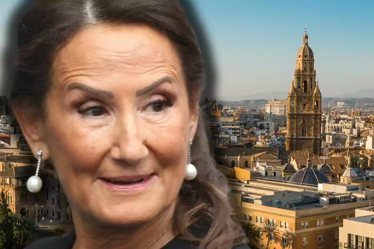 Close-up of Paloma Rocasolano wearing pearl earrings, with a city and a prominent cathedral in the background