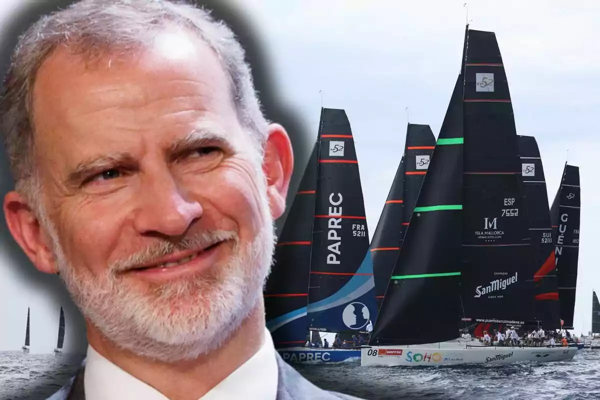 Felip VI somriu en primer pla mentre al fons es veuen diversos velers de competició navegant pel mar.