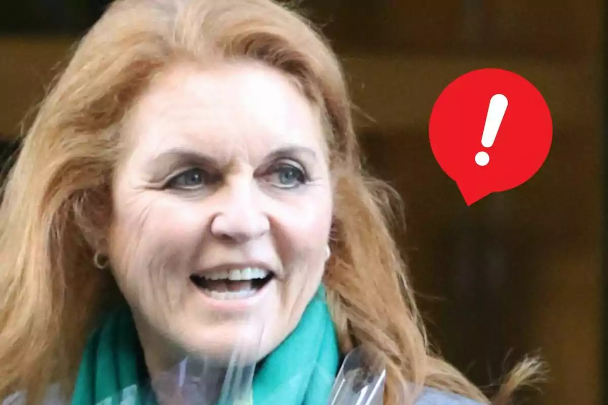 Sarah Ferguson somrient amb una bufanda verda i una icona d’advertència vermella amb un signe d’exclamació al seu costat