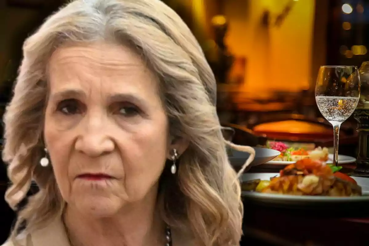 La infanta Elena amb expressió seriosa en primer pla amb un restaurant elegant i plats de menjar al fons