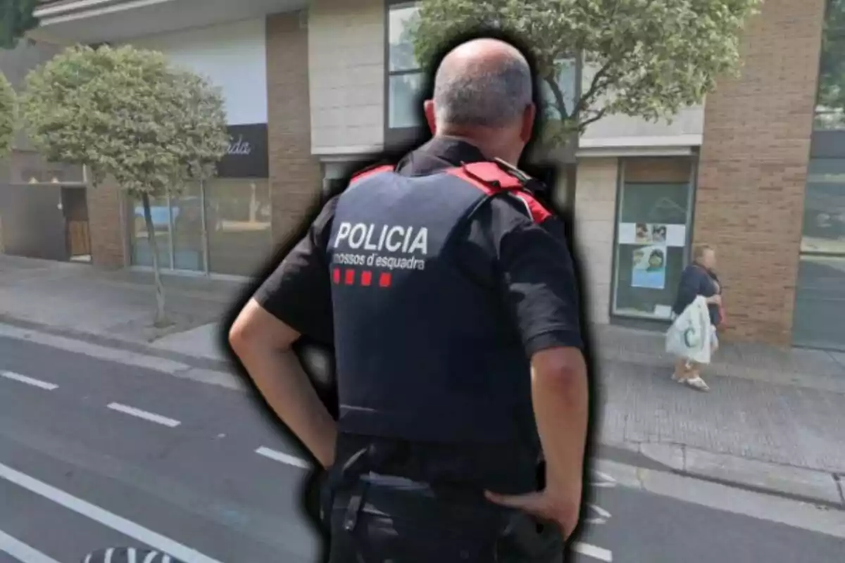 Agent dels Mossos d'Esquadra d'esquena en un carrer urbà amb edificis i arbres
