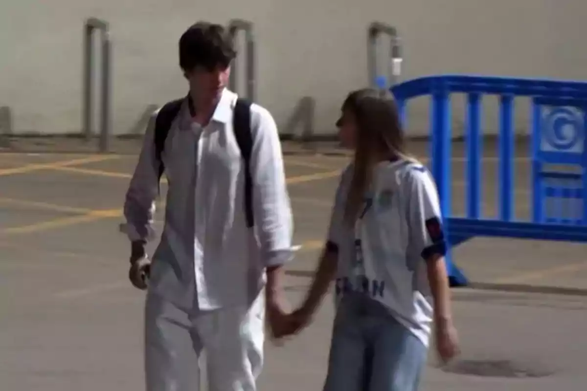 Pablo Urdangarin i Johanna Zott caminen de la mà en un aparcament, el noi porta una camisa blanca i motxilla, la noia porta una samarreta esportiva i texans. Pablo Urdangarin i Johanna Zott caminen de la mà en un aparcament, el noi porta una camisa blanca i motxilla, la noia porta una samarreta esportiva i texans.