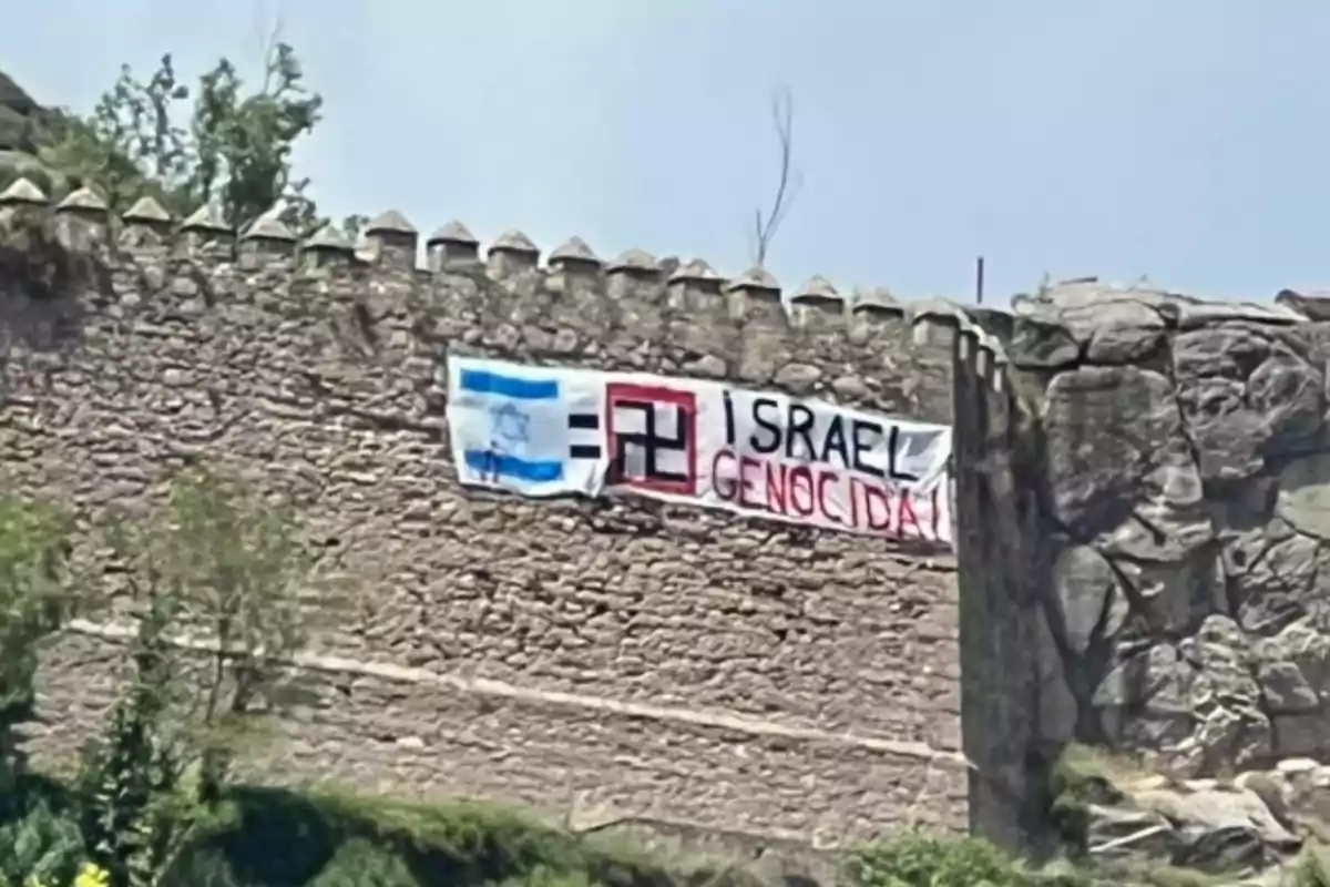 Pancarta penjada en una muralla de pedra amb missatges i símbols en contra d’Israel