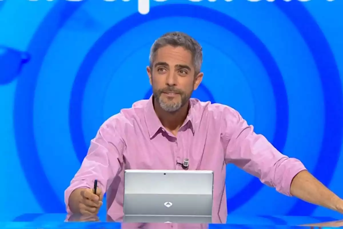 Roberto Leal con camisa rosa sentado frente a una computadora en un set de televisión con fondo azul. Captura de 'Pasapalabra' Roberto Leal con camisa rosa sentado frente a una computadora en un set de televisión con fondo azul. Captura de 'Pasapalabra'