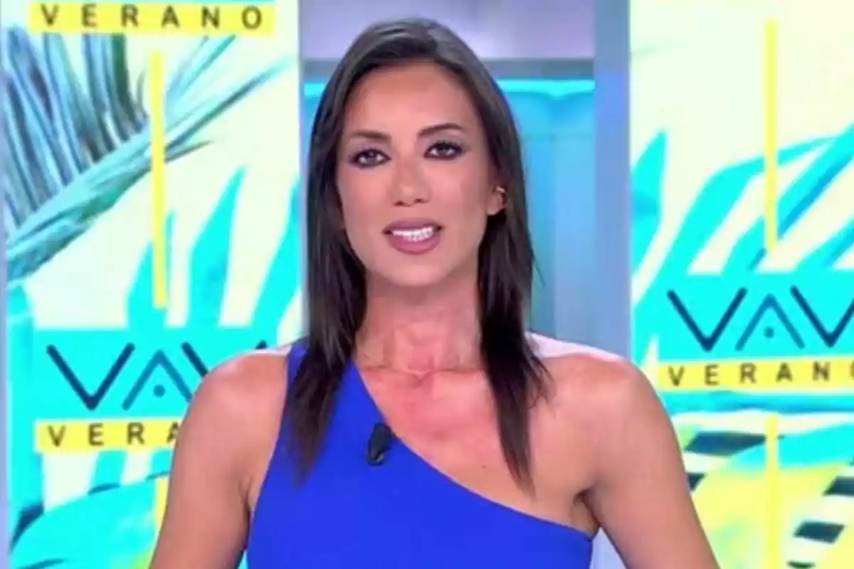 Patricia Pardo con cabello lacio y oscuro usando un vestido azul de un solo hombro en un set de Vamos a ver con fondo colorido y la palabra verano visible Patricia Pardo con cabello lacio y oscuro usando un vestido azul de un solo hombro en un set de Vamos a ver con fondo colorido y la palabra verano visible