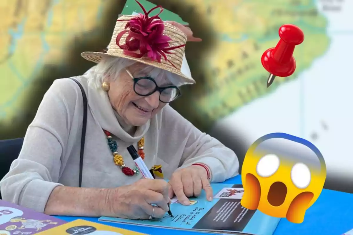 Dona gran somrient amb barret i ulleres signant un llibre en una taula blava, amb un mapa de fons, una xinxeta vermella i un emoji de sorpresa