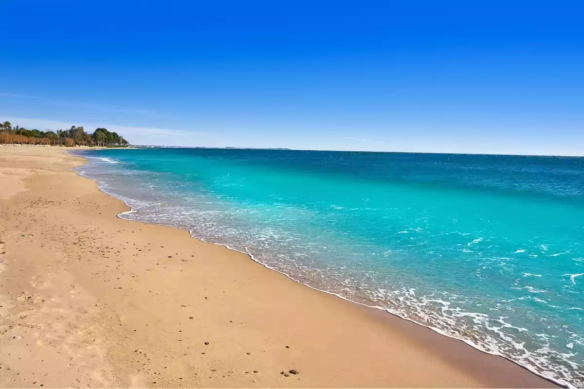 Platja de sorra daurada amb aigua turquesa i cel serè