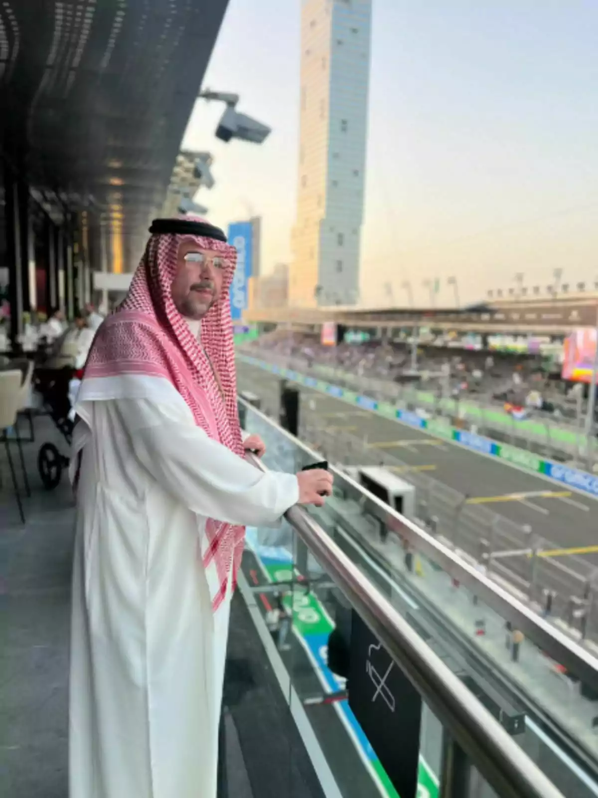 Abdullah bin Saad in traditional Arab attire watching a racetrack from a balcony in a modern building Abdullah bin Saad in traditional Arab attire watching a racetrack from a balcony in a modern building