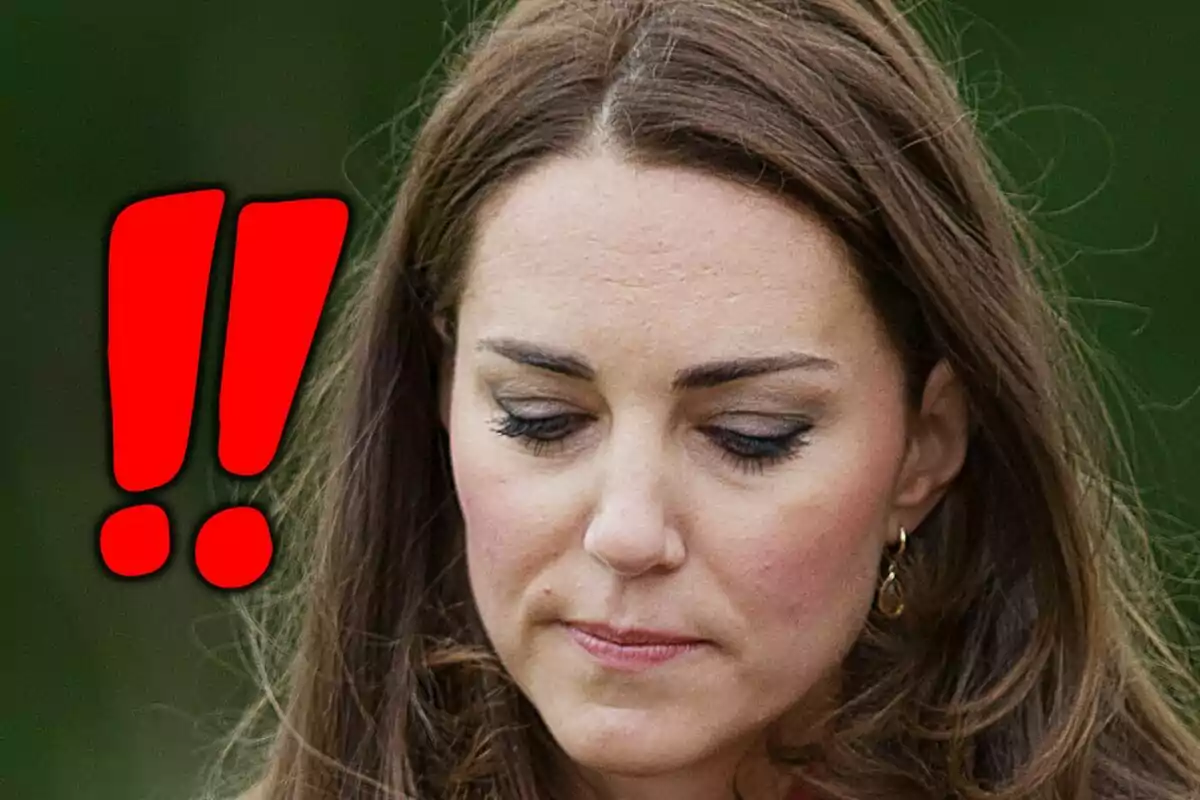 Primer pla de Kate Middleton mirant cap avall amb expressió seriosa i dos signes d’exclamació vermells a l’esquerra.