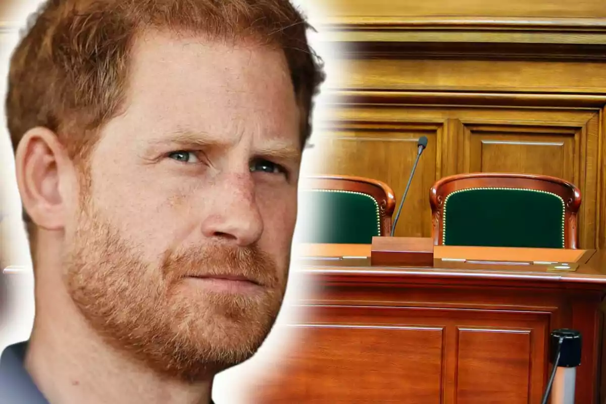 Un home pèl-roig amb barba apareix en primer pla amb una expressió seriosa i al fons s’observa una sala de tribunal amb cadires i un micròfon.