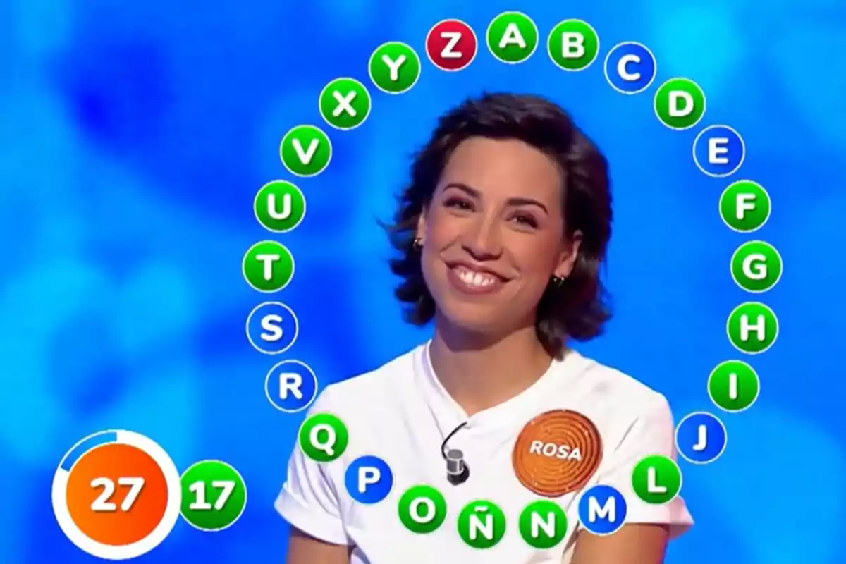 Rosa Rodríguez sonriente participando en Pasapalabra con letras del abecedario rodeándola y un marcador de tiempo y aciertos en la esquina inferior izquierda Rosa Rodríguez sonriente participando en Pasapalabra con letras del abecedario rodeándola y un marcador de tiempo y aciertos en la esquina inferior izquierda