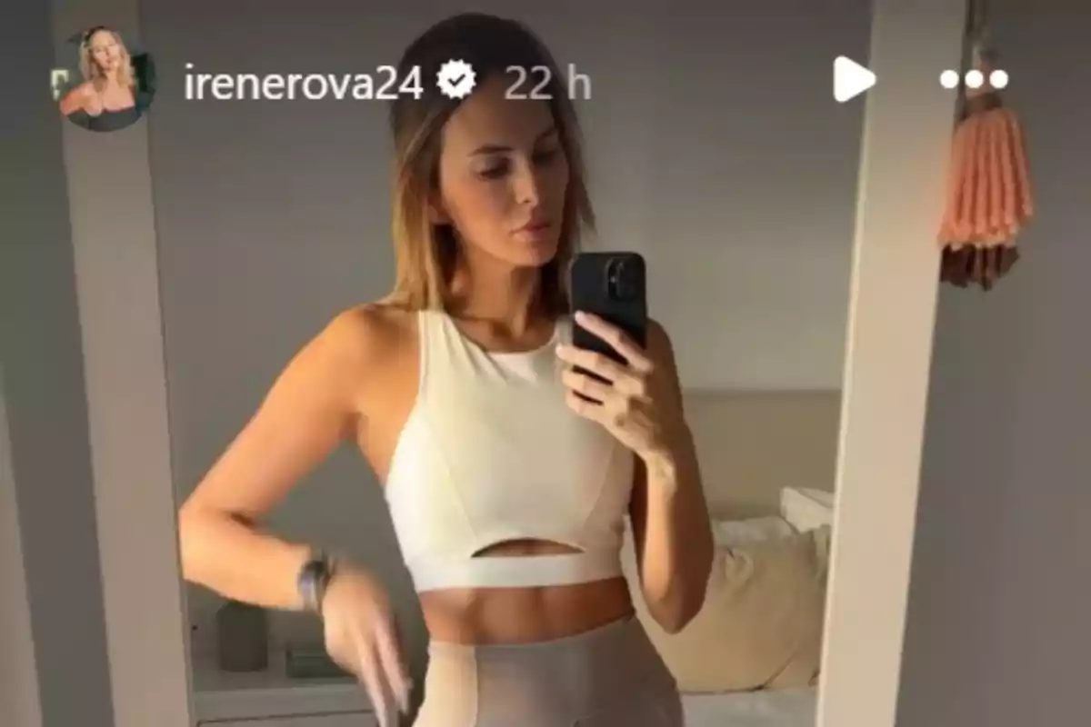 Irene Rosales tomándose una selfie frente a un espejo usando ropa deportiva clara en una habitación iluminada Irene Rosales tomándose una selfie frente a un espejo usando ropa deportiva clara en una habitación iluminada
