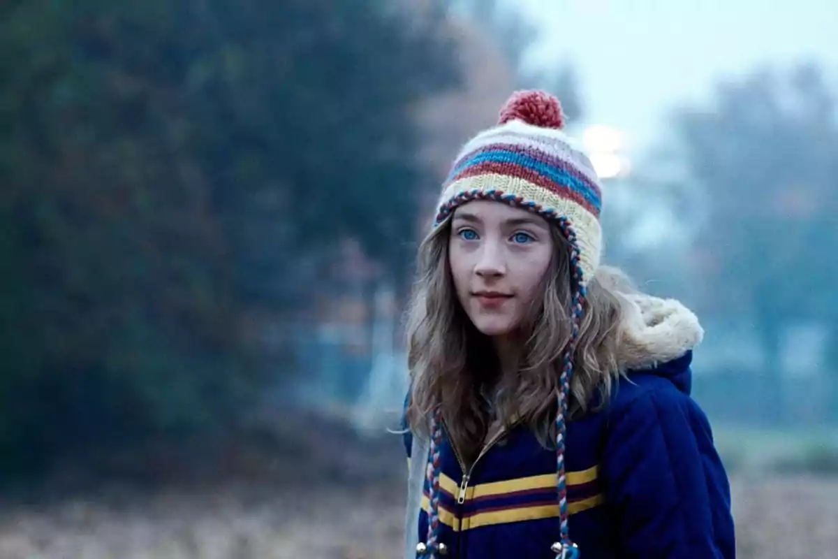Joven con gorro de lana colorido y chaqueta azul en un entorno al aire libre y frío Joven con gorro de lana colorido y chaqueta azul en un entorno al aire libre y frío