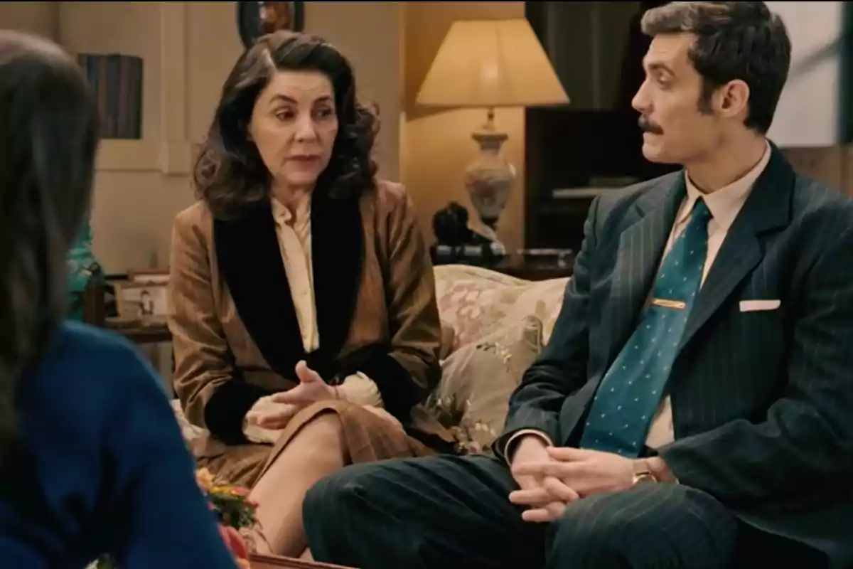 Digna y Joaquín elegantemente vestidas conversan sentadas en un sofá en una sala iluminada con una lámpara de mesa al fondo. Captura de 'Sueños de libertad' Digna y Joaquín elegantemente vestidas conversan sentadas en un sofá en una sala iluminada con una lámpara de mesa al fondo. Captura de 'Sueños de libertad'