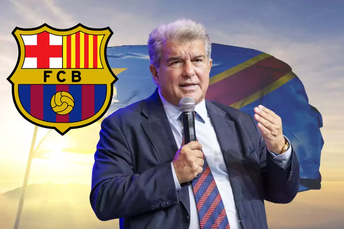 Home amb vestit parlant amb micròfon davant d’una bandera i l’escut del FC Barcelona
