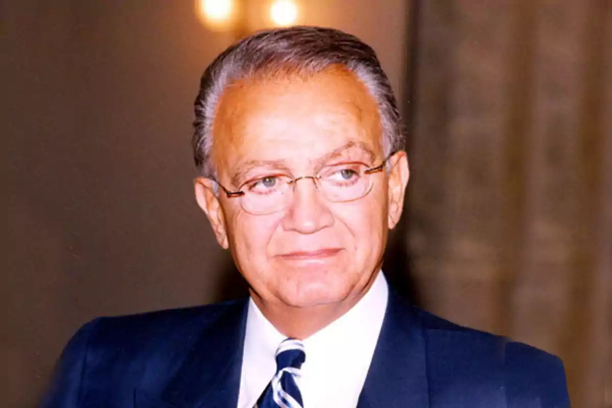 Wafic Saïd vestint un vestit blau i una corbata de ratlles en un entorn interior il·luminat Wafic Saïd vestint un vestit blau i una corbata de ratlles en un entorn interior il·luminat