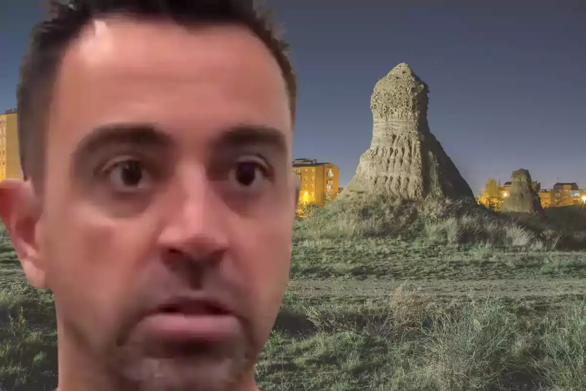Primer pla d’un home amb expressió seriosa davant d’un paisatge nocturn amb una formació rocosa i edificis al fons