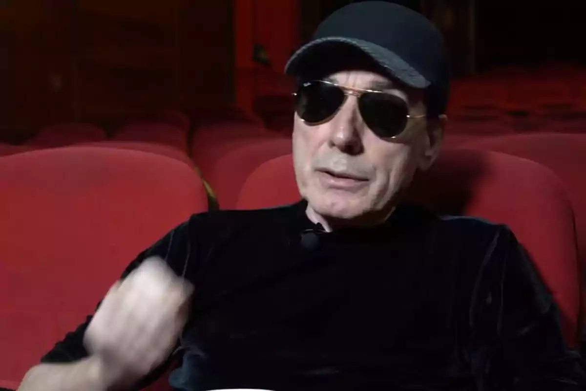 Eusebio Poncela amb ulleres de sol i gorra negra assegut en una butaca vermella de cinema Eusebio Poncela amb ulleres de sol i gorra negra assegut en una butaca vermella de cinema