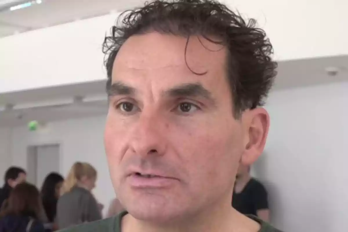 Félix Gorner en primer pla amb expressió seriosa en un entorn interior on hi ha diverses persones desenfocades al fons Félix Gorner en primer pla amb expressió seriosa en un entorn interior on hi ha diverses persones desenfocades al fons
