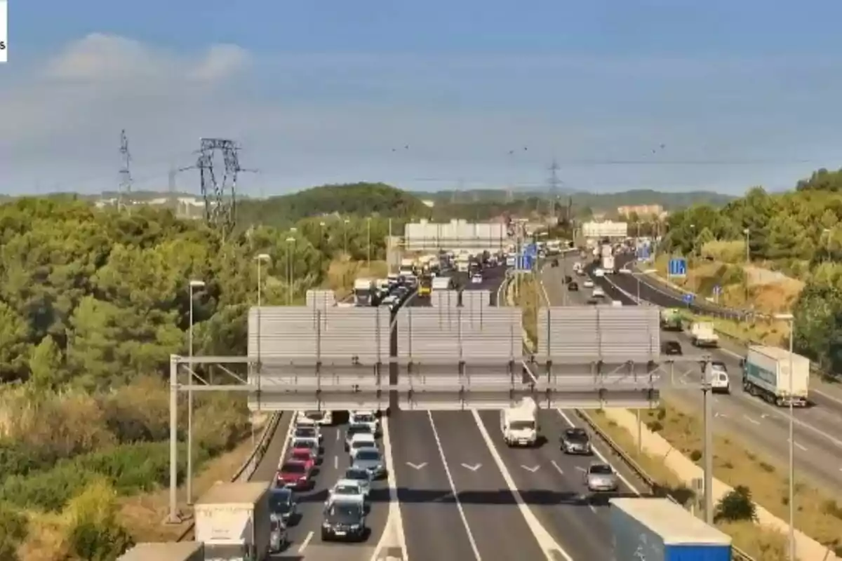 Carretera amb trànsit dens en diversos carrils envoltada d’arbres i turons sota un cel serè