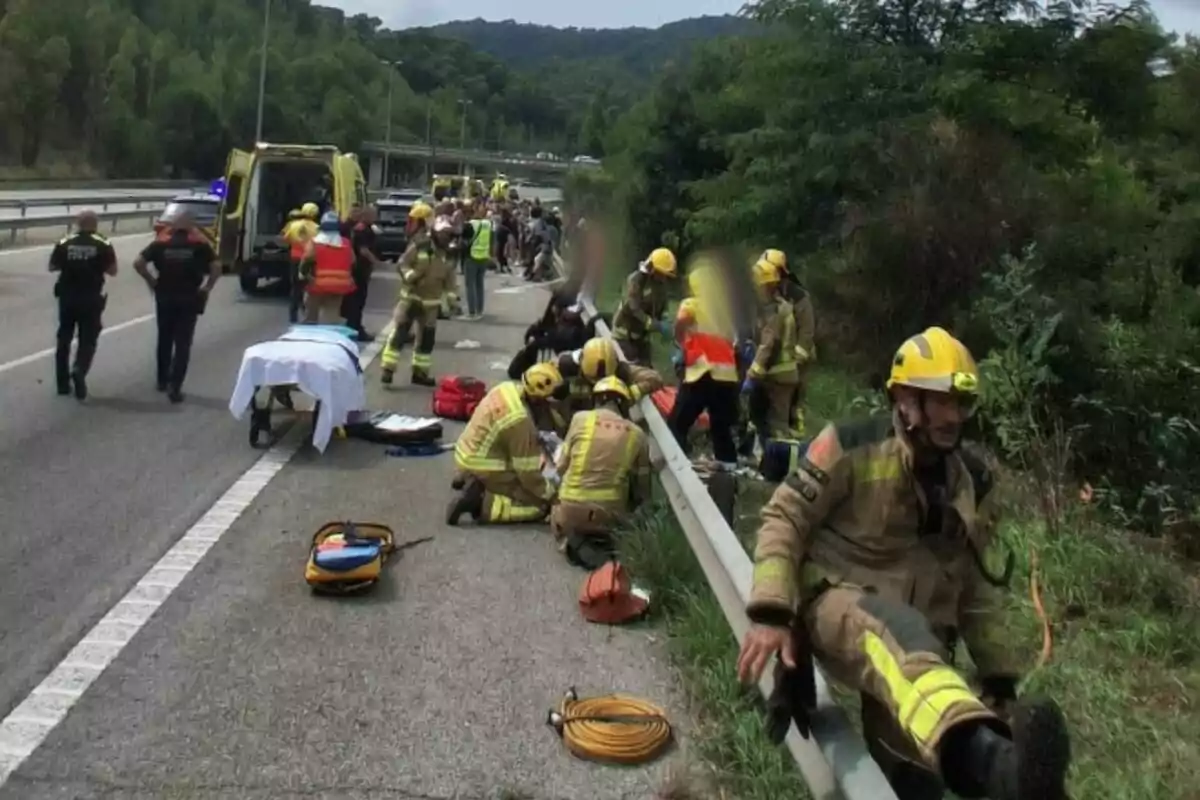 Diversos bombers i personal d’emergència atenen ferits a l’arcèn d’una carretera al costat d’ambulàncies i patrulles policials després d’un accident. Diversos bombers i personal d’emergència atenen ferits a l’arcèn d’una carretera al costat d’ambulàncies i patrulles policials després d’un accident.