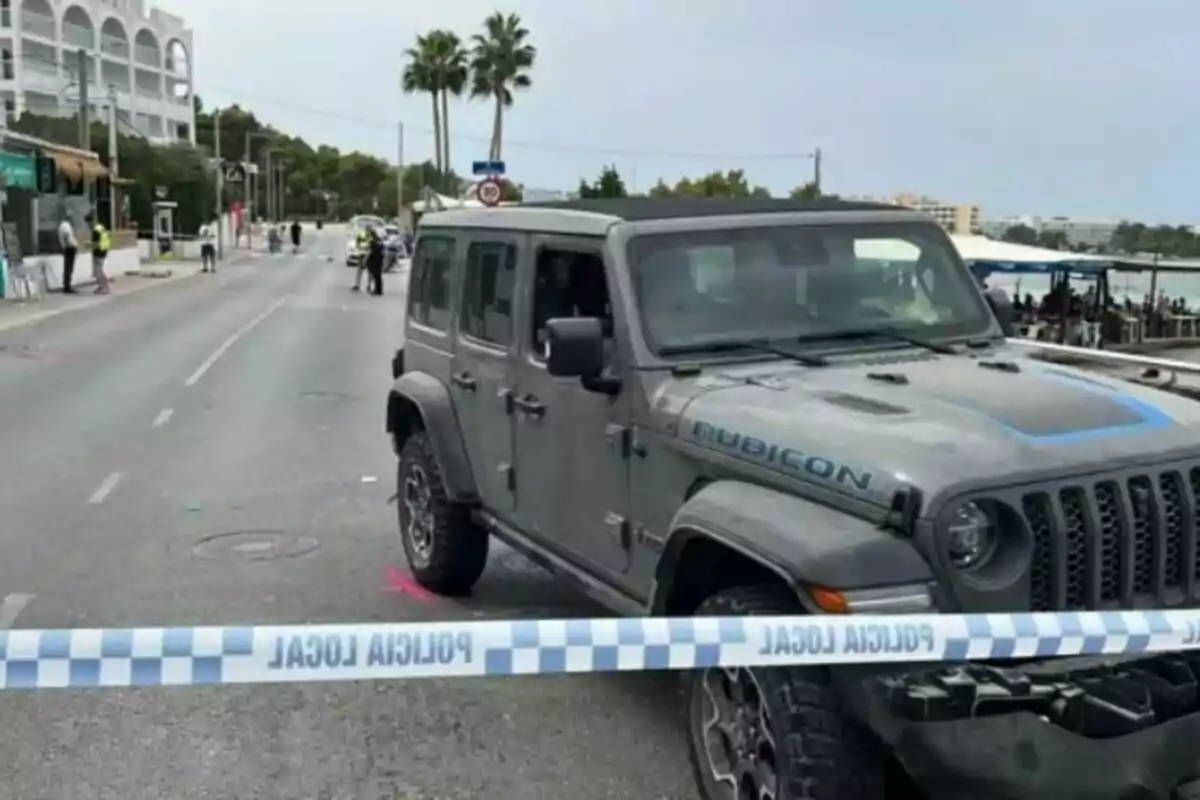 Jeep gris aturat en un carrer acordonat per la policia local amb diversos agents i persones al fons