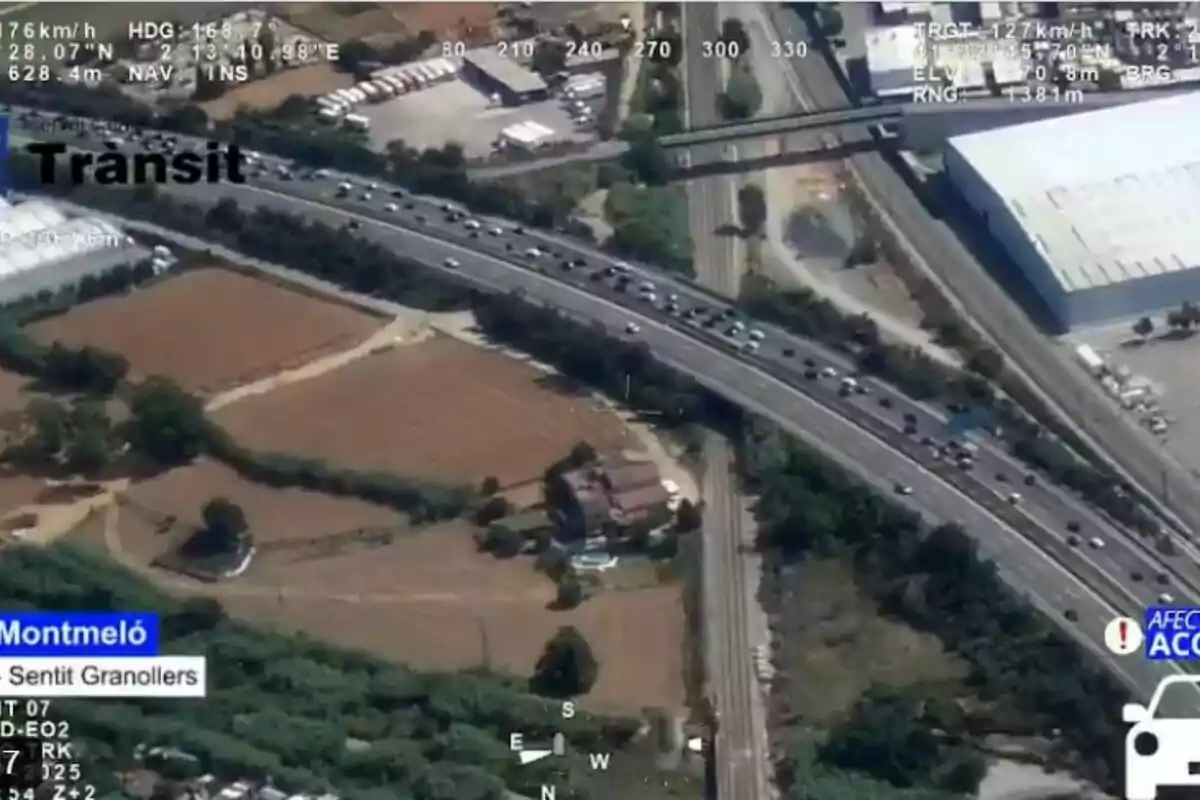 Imatge aèria d’una autopista amb trànsit dens a prop de Montmeló en direcció a Granollers, envoltada de camps i edificis industrials.