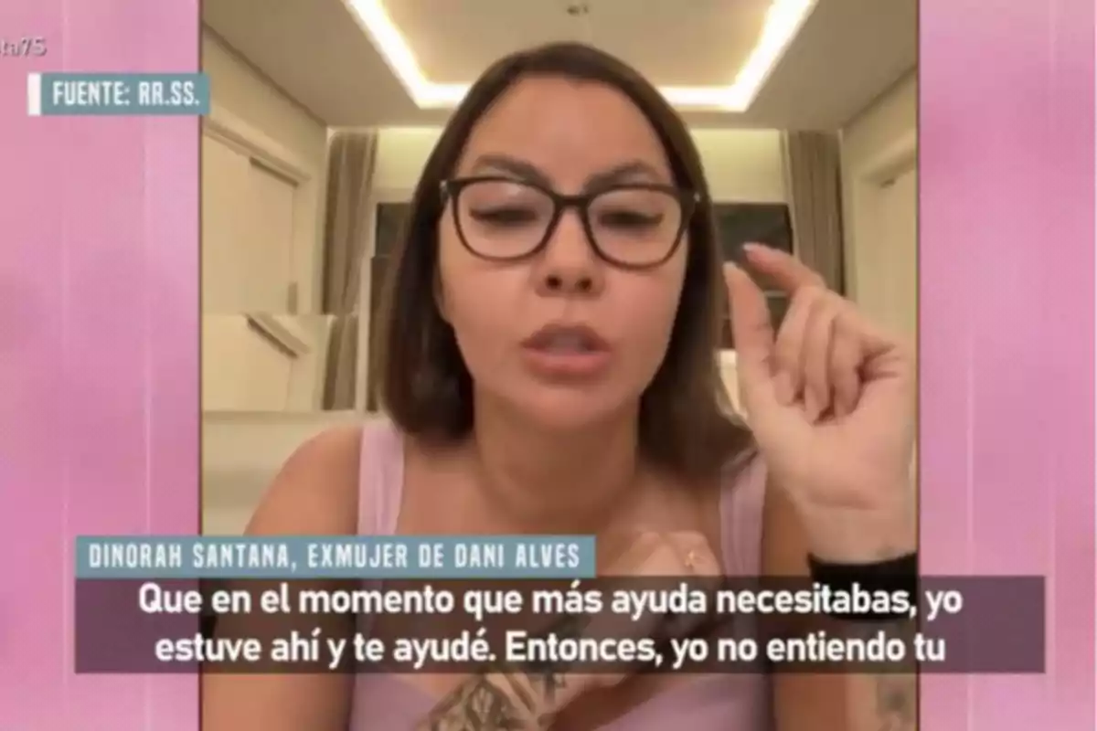 Mujer con gafas y cabello lacio hablando frente a la cámara en una habitación iluminada, con subtítulos en la parte inferior de la imagen Mujer con gafas y cabello lacio hablando frente a la cámara en una habitación iluminada, con subtítulos en la parte inferior de la imagen