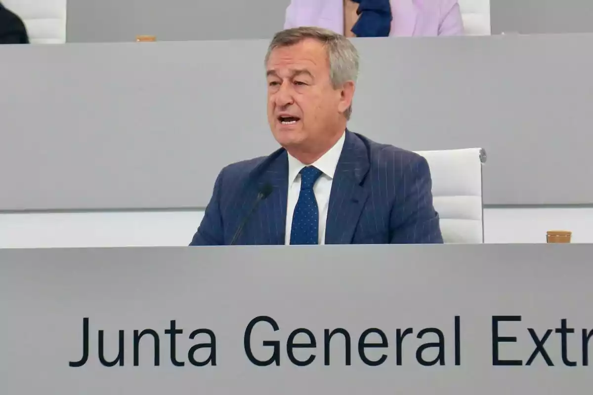 Hombre de traje hablando en una junta general extraordinaria sentado frente a un micrófono