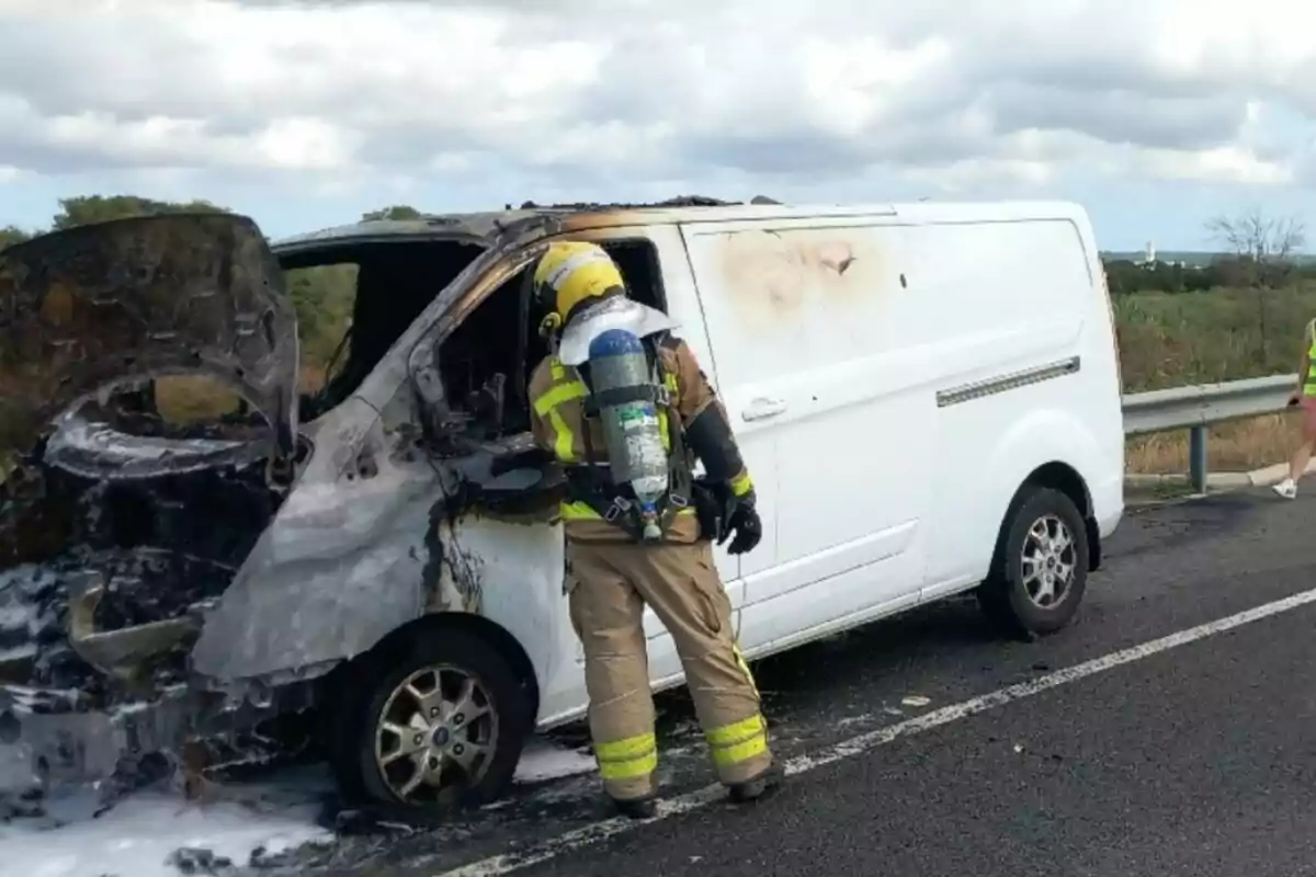 Un bombero revisa una camioneta blanca quemada en una carretera